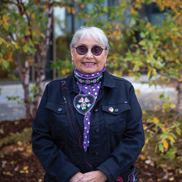 A photo of indigenous elder - Marie Short - posing outside of Lambton College.