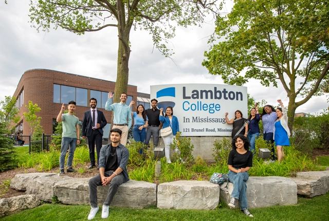 A group of students posing for a photo with the Mississauga Campus sign.
