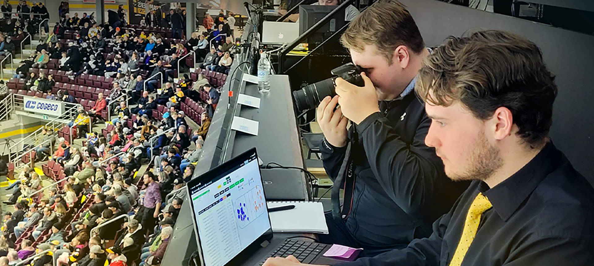Two white men analyzing data and taking photos at a hockey game