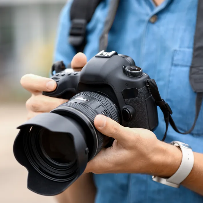 A close-up image of an international student holding a digital camera.