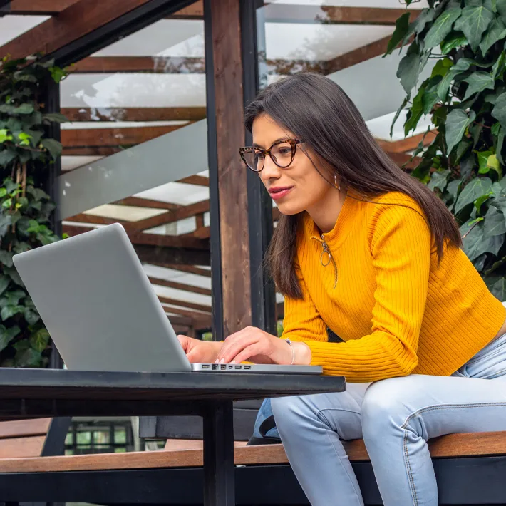 Women sitting outside with computer wearing glasses.