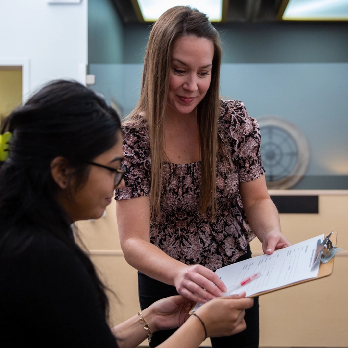 Receptionist hands student paperwork