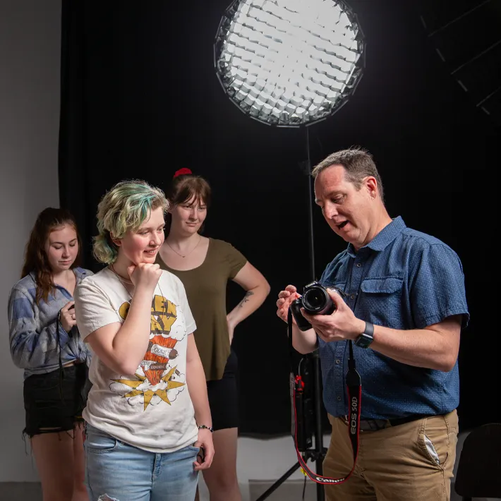 Highschool students in photography studio with teacher.