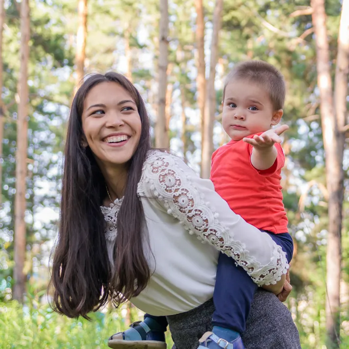 An indigenou woman and her child laughing and smiling for photo outdoors.