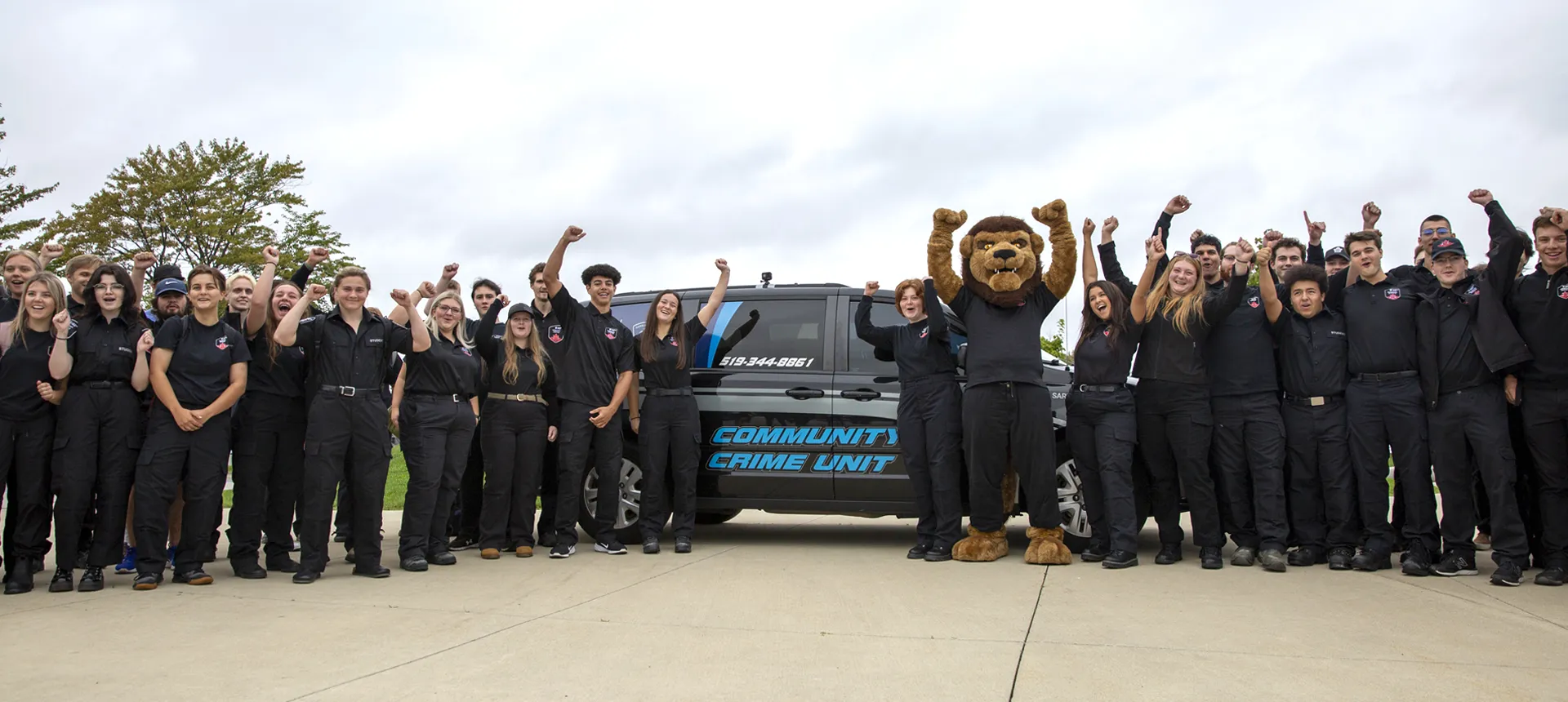 Students and Pounce standing beside a community crime unit van.