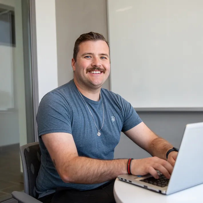 A photo of a student on computer in a campus boardroom.