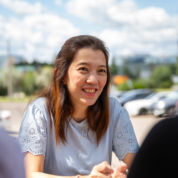 -A student outside the Queens campus sitting and smiling.