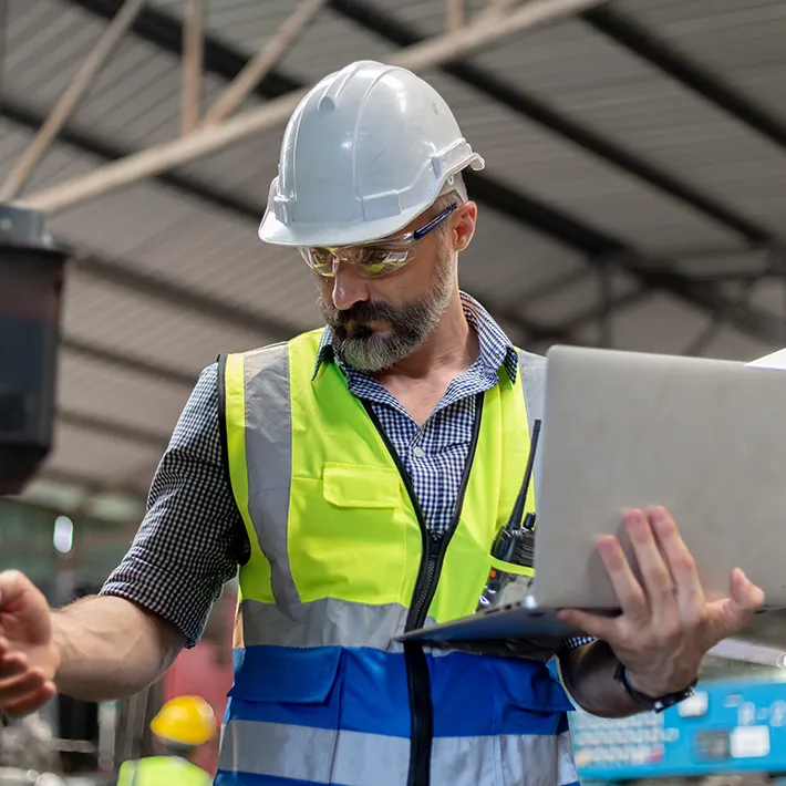 Man in safety vest holding a laptop