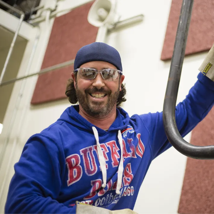 A student posing for photo while working on piping.