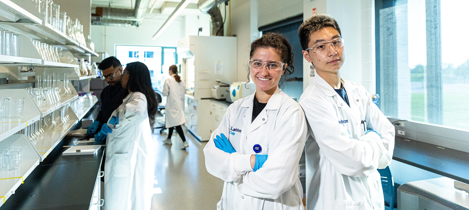 Students wearing white lab coats in the research facility.