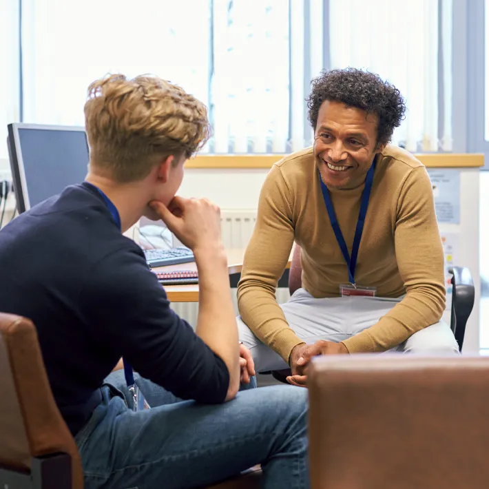 A students sits with teach in a private office to discuss support services.