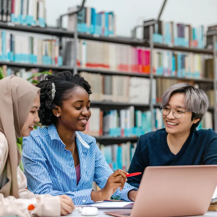 International students sitting around a table looking at notes and laughing.