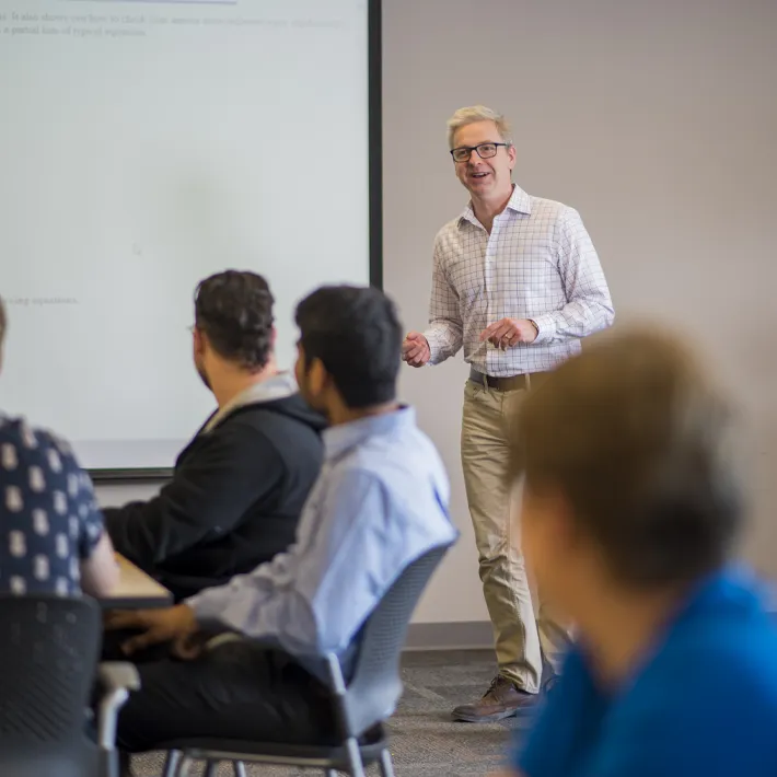 Professor at the front of the classroom teaching a class.