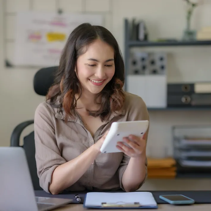 Bookkeeper student using calculator while sitting at desk.