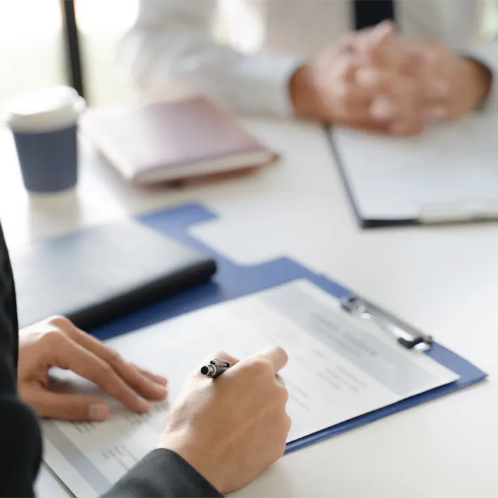 Close up photo of a human resource employee reviwing a resume on desk.