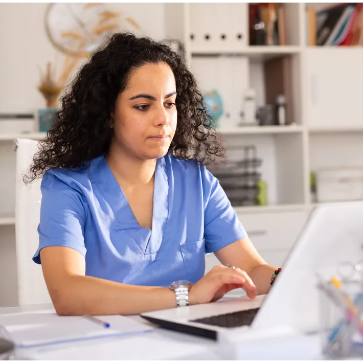 Medical Clerk sitting at desk filing medical records on computer.