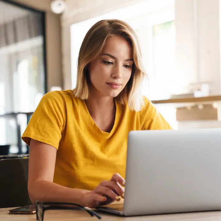 Women on laptop typing at desk.