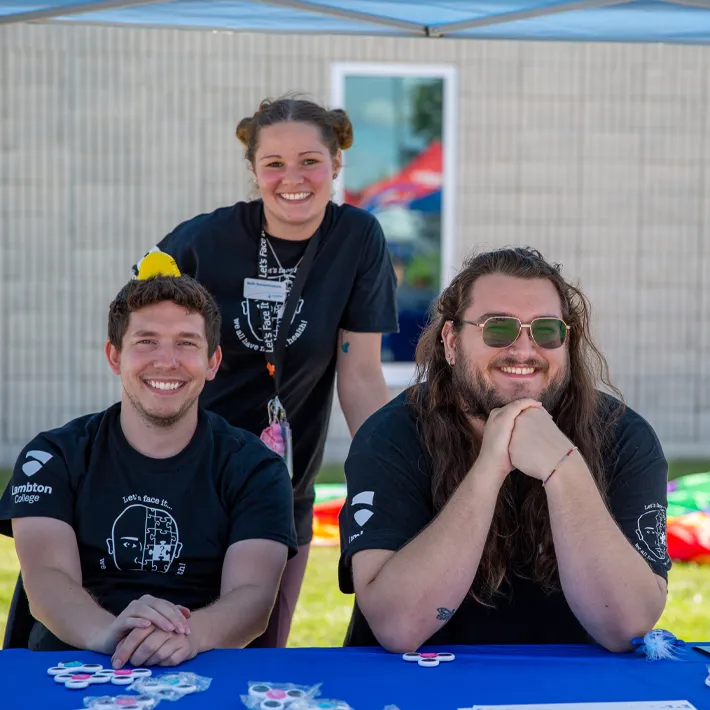 Students sitting at booth for Lets Face It event.