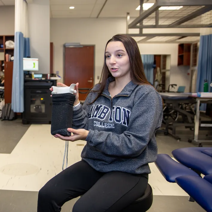 A student holding a prop in lab and posing for photo.