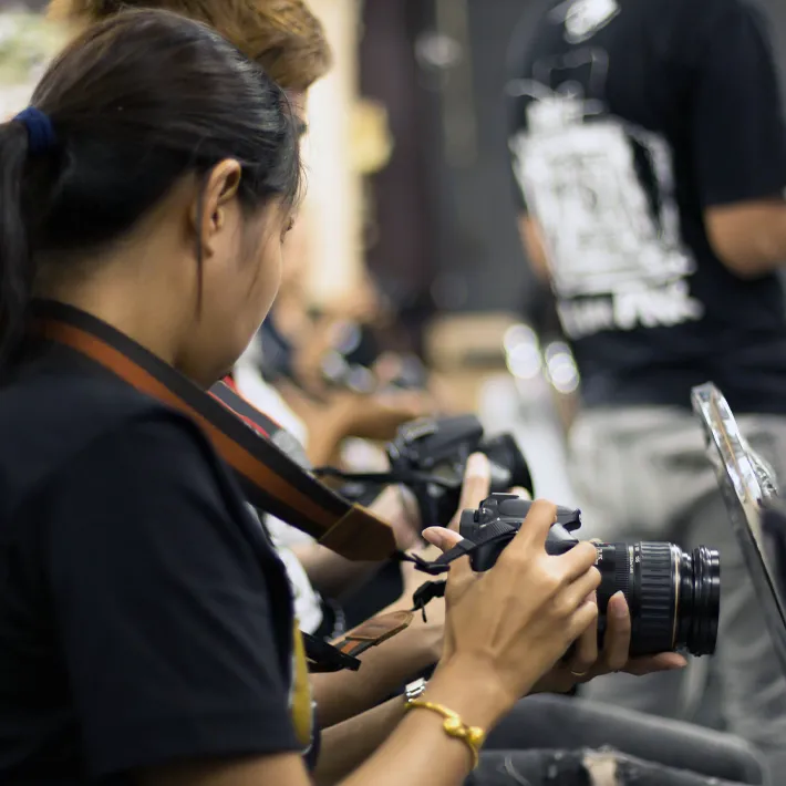 Photography students in class reving photography settings.