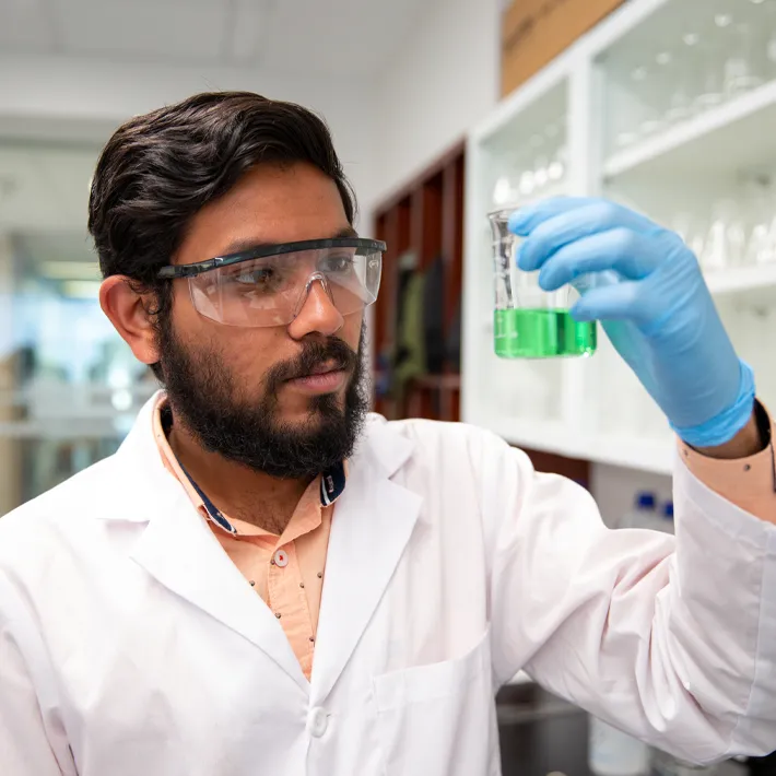 Student in chemical lab testing liquids.