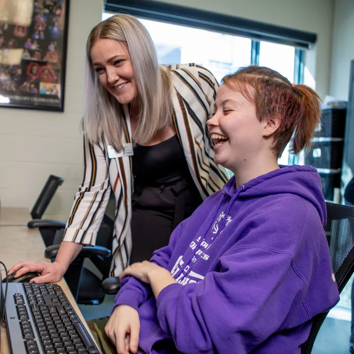 A teacher showing a student lesson on computer and laughing. 