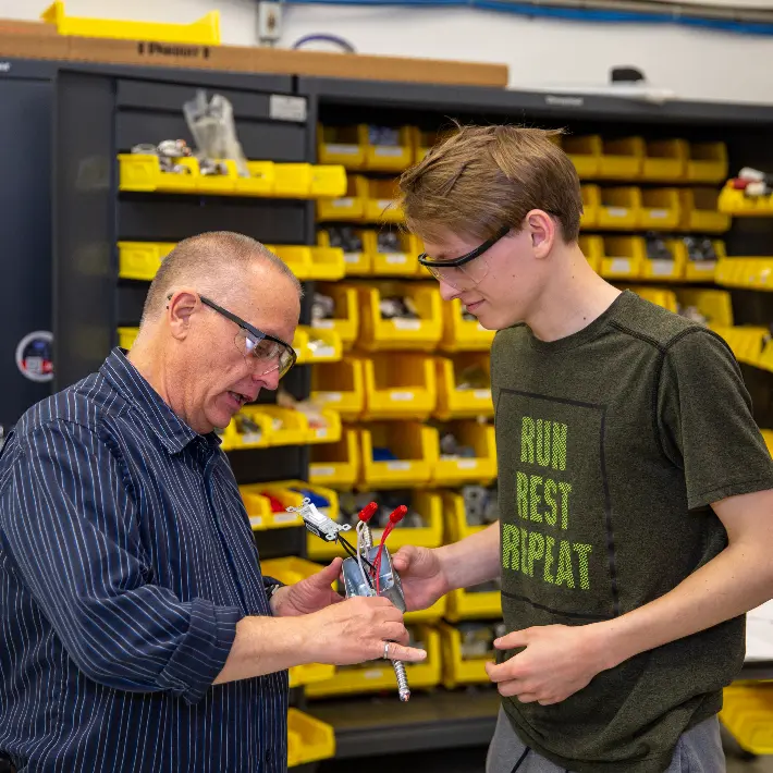 Residential electrical dual credit student with teacher in shop.